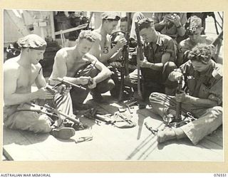 AT SEA. 1944-10-07. PERSONNEL OF THE 36TH INFANTRY BATTALION CLEANING AND CHECKING THEIR SMALL ARMS ABOARD THE DUTCH TROOPSHIP "SWEARTENHONDT" AS THE VESSEL NEARS THE NEW BRITAIN COAST. IDENTIFIED ..