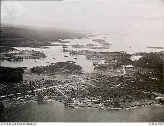 Madang, New Guinea, 1945-10. Aerial view of Madang Harbour showing (in the foreground) the camp site for Headquarters, RAAF Northern Command (NORCOM). At centre, three ships and two Consolidated ..