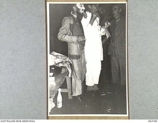 RAMU VALLEY, NEW GUINEA. 1944-01-01. MEMBERS OF THE 7TH DIVISION CONCERT PARTY "MAKING UP" FOR THEIR SHOW. THEY ARE: CORPORAL T. (IKE) CALING (1); LIEUTENANT R. STEIN, OFFICER COMMANDING (2); ..