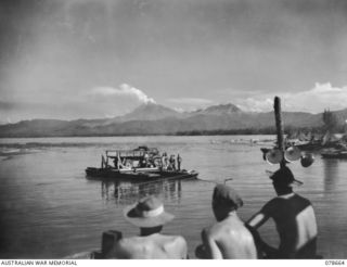 MOTUPENA POINT, BOUGAINVILLE ISLAND, 1945-01-26. ENGINEERS OF THE 23RD FIELD COMPANY, WORKING ON THE NEW TIMBER PILE BRIDGE ACROSS THE JABA RIVER WATCHING THE OLD PONTOON FERRY TRANSPORTING AN ARMY ..