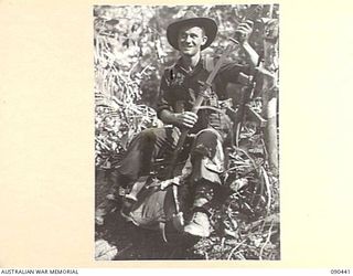 WONGINARA MISSION, NEW GUINEA. 1945-04-04. SERGEANT J.J. RICHARDS, 2/3 INFANTRY BATTALION DISPLAYS A JAPANESE SWORD AND FLAG FOLLOWING HIS RETURN FROM FORWARD POSITIONS IN THE TORRICELLI MOUNTAINS, ..