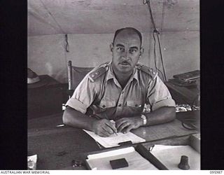 CAPE WOM, WEWAK AREA, NEW GUINEA. 1945-09-01. LIEUTENANT COLONEL W.H. MENCE, CORPS OF ELECTRICAL AND MECHANICAL ENGINEERS, HEADQUARTERS 6 DIVISION AT HIS DESK