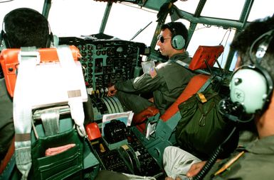 CPT Wayne Shatz, right, 374th Tactical Airlift Wing, and his crew members prepare to airdrop packages from their C-130 Hercules aircraft during a Christmas Drop mission. The annual airdrop is a humanitarian effort providing aid to needy islanders throughout Micronesia during the holiday season