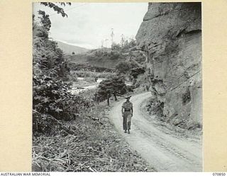WAU - LAE ROAD, NEW GUINEA, 1944-02-20. A SECTION OF THE ROAD 6 MILES FROM WAU WHICH LIES TO THE REAR. THE BULOLO RIVER AND ROAD IS PICTURED IN THE MIDDLE DISTANCE