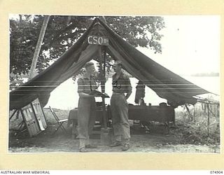 MADANG, NEW GUINEA. 1944-07-22. NX112671 CAPTAIN C.W. POWDITCH, G111 OPERATIONS (1) AND VX74779 CAPTAIN C.C. GUY G111 INTELLIGENCE (2) OUTSIDE THE G111 OPERATIONS TENT AT HEADQUARTERS 5TH DIVISION