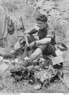 RAMU VALLEY, NEW GUINEA, 1943-10-20. NX58832 LIEUTENANT E.F. BYRNE OF THE 2/7TH AUSTRALIAN INDEPENDENT COMPANY, EATING LUNCH FROM HIS FIELD OPERATIONS RATION