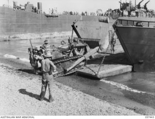 FINSCHHAFEN, NEW GUINEA, 1943-09-22. UNLOADING A FINSCHHAFEN FORCE BULLDOZER FROM A SMALL CRAFT, PRIOR TO LOADING IT INTO AN LST (LANDING SHIP, TANK)