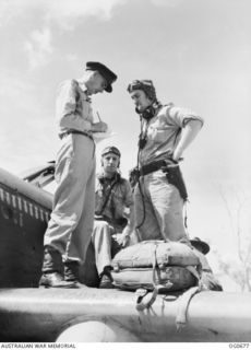 NADZAB, NEW GUINEA. C. 1944-02. FLYING OFFICER (FO) J. JOHNSON, BATHURST, NSW, INTELLIGENCE OFFICER (LEFT), TAKING REPORTS OF DIVE BOMBING OVER HANSA BAY FROM FO G. L. STEVENSON, NEWCASTLE, NSW, ..
