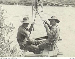 BUTIBUM, NEW GUINEA. 1944-11-27. NX95472 LIEUTENANT F.S. WOOD, CINE PHOTOGRAPHER, MILITARY HISTORY SECTION AND A COMPANION CROSSING THE FAST FLOWING BUSU RIVER IN ORDER TO GET TO THE BUTIBUM ..