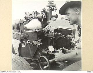 MARKHAM VALLEY, NEW GUINEA. 1944-08-28. VX67232 GUNNER F.J. COPLAND, GUNLAYER OF 12 BATTERY, 4TH FIELD REGIMENT, LAYING A 25 POUNDER GUN