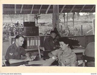 LAE, NEW GUINEA. 1945-05-20. CORPORAL N.C. COLLARD (1), AND SERGEANT J.E. POLLARD (2), CHECKING THE PURCHASE AND SHIPMENT CONTROL RECORDS AT HEADQUARTERS AUSTRALIAN ARMY CANTEEN SERVICE