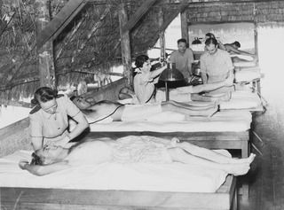 1943-04-01. NEW GUINEA. PHYSIOTHERAPY. AT AN AUSTRALIAN GENERAL HOSPITAL IN NEW GUINEA WHICH HAS TAKEN OVER A SPECIALLY CONSTRUCTED NATIVE HUT TO CARRY OUT REHABILITATION TREATMENT - THE AIM OF ..