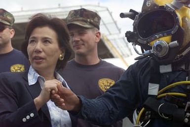 Her Excellency Makiko Tanaka, Minister of Foreign Affairs, Japan, shakes hands with US Navy (USN) CHIEF Boatswains Mate (BMC), Diver (DV) Robert Lastimosa, from Mobile Diving and Salvage Unit One (MDSU-1) after he presents her with a Navy divers coin. Mrs. Tanaka came to lend her support and received an update on the USN led effort during recovery operations for the Japanese fishing vessel Ehime Maru