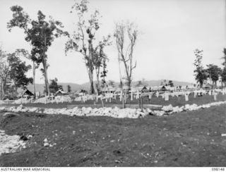 CAPE MOEM, NEW GUINEA. 1945-10-23. A SECTION OF THE WEWAK WAR CEMETERY. IN BACKGROUND, AUSTRALIAN NEW GUINEA ADMINISTRATIVE UNIT NATIVES, WORKING FOR 7 WAR GRAVES UNIT, ARE PREPARING NEW GRAVES