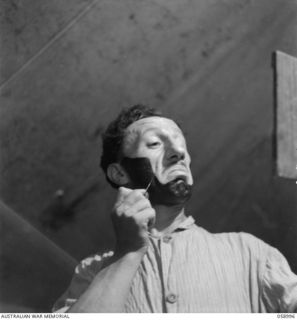 KONEDOBU (KANEDABU), NEW GUINEA. 1943-10-27. VX8368 CORPORAL (CPL) T. CALING, AN ORIGINAL MEMBER OF THE 7TH AUSTRALIAN DIVISION CONCERT PARTY, MAKING UP FOR THE NIGHT'S SHOW. CPL CALING ..