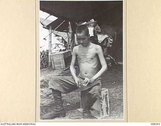 MUSCHU ISLAND, NEW GUINEA. 1945-10-27. A JAPANESE HOSPITAL ORDERLY MAKING BEDPANS OUT OF DISUSED BISCUIT TINS. THIS WAS ONE OF THE INSTRUCTIONS BY AUSTRALIAN MEDICAL OFFICERS WHO INSPECTED THE ..
