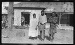 Two men and a woman in torn clothes, outside a building