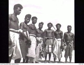 KILA, NEW GUINEA. 1943-10-24. BARE-CHESTED NATIVE LABOURERS OF THE LABOUR CAMP LINED UP WITH THEIR GIFTS FROM THE WOMEN IN AUSTRALIA