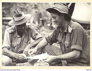 CAPE CUNNINGHAM, NEW BRITAIN, 1944-12-16. LIEUTENANT A R RULE, (1), AND LT B T LIPSCOMBE, (2), 2/2 FORESTRY COY, DISCUSSING TIMBER