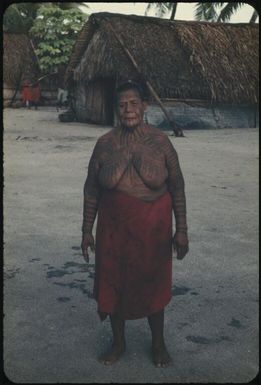 An older woman with body decoration standing outside a village house : Tasman Islands, Papua New Guinea, 1960 / Terence and Margaret Spencer