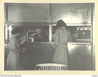 PORT MORESBY, PAPUA, 1944-02-20. MEMBERS OF THE AUSTRALIAN ARMY MEDICAL WOMEN'S SERVICE PURCHASING GOODS FROM THE CANTEEN IN THE AUSTRALIAN WOMEN'S SERVICES CLUB, CONDUCTED BY THE AUSTRALIAN ARMY ..