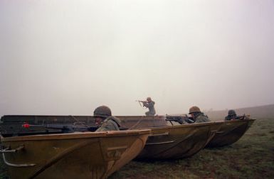 Members of Company A, 65th Engineer Battalion, 25th Infantry Division, protect their light tactical raft from an opposing force attack during training Exercise OPPORTUNE JOURNEY 4-83, at the US Army's Pohakuloa Training Area
