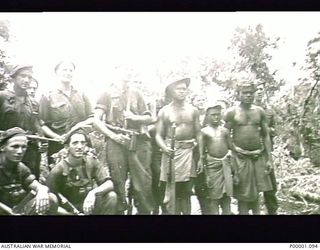 THE SOLOMON ISLANDS, 1945. A GROUP OF AUSTRALIAN SERVICEMEN AND NATIVE PORTERS ON THE NUMA NUMA TRAIL ON BOUGAINVILLE ISLAND. (RNZAF OFFICIAL PHOTOGRAPH.)