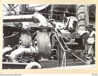 RABAUL, NEW BRITAIN. 1945-09-30. R.J. SUMMERS (1) AND R.W. BERWICK, SALVAGE ENGINEER (2), MEMBERS OF COMMONWEALTH MARINE SALVAGE BOARD WITH TWO EXTRA WATER PUMPS READY FOR USE ON THE JAPANESE ..