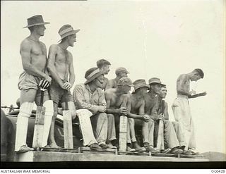 VIVIGANI, GOODENOUGH ISLAND, PAPUA. 1943-12-26. AIRMEN OF NO. 30 (BEAUFIGHTER) SQUADRON RAAF, SITTING ON TOP OF A PETROL TANKER WAITING TO GO INTO BAT IN A GAME OF CRICKET. THE SCORER IS ON THE ..