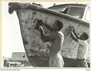 PAPUA, NEW GUINEA. 1942-07-27. MEN OF THE ROYAL AUSTRALIAN AIR FORCE MARINE SECTION AT WORK AT THEIR SEAPLANE BASE. HERE THEY ARE SHOWN REPAIRING A FLYING-BOAT TENDER