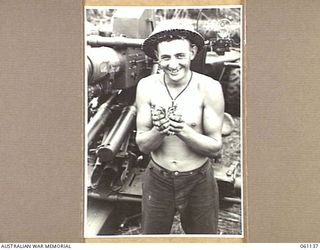 DUMPU AIRSTRIP, NEW GUINEA. 1943-11-14. QX18075 GUNNER K. J. BLINCO OF MILERRMAN, QLD AND THE 2/4TH AUSTRALIAN LIGHT ANTI-AIRCRAFT REGIMENT HOLDING SOME WILD DUCKLING SHE HAS JUST CAUGHT