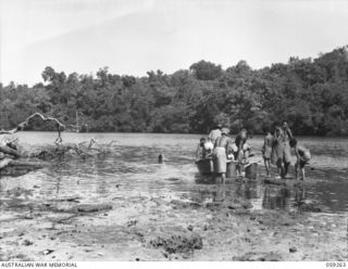 MALASIGE, NEW GUINEA, 1943-10-23. NATIVE VILLAGERS AND THEIR BUCKETS AT THE LAGOON NEAR THE VILLAGE