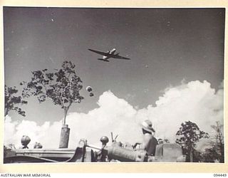 SOUTH BOUGAINVILLE. 1945-07-24. A BULLDOZER OPERATING A RAFT ACROSS THE MOBIAI RIVER CARRYING 29 INFANTRY BRIGADE SUPPLIES. A DOUGLAS C47 DAKOTA TRANSPORT AIRCRAFT FLIES OVERHEAD TO DROP FOOD ..