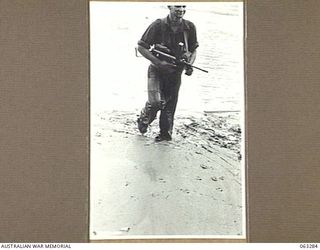 RAMU RIVER, FAITA AREA, NEW GUINEA. 1944-01-07. WX12530 TROOPER L. ANDERSON OF KALGOORLIE, WA, AND OF THE 2/2ND COMMANDO SQUADRON WADING THROUGH THE MUD ON THE EDGE OF THE RAMU RIVER AS HE RETURNS ..