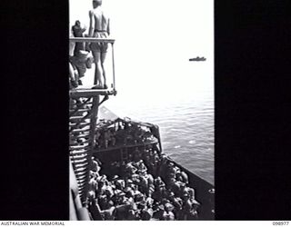 WEWAK HARBOUR, NEW GUINEA, 1945-11-25. TROOPS OF 6 DIVISION EMBARKING ON HMAS SHROPSHIRE FROM LANDING BARGES.THEY ARE RETURNING TO AUSTRALIA FOR DISCHARGE