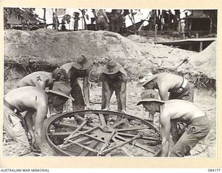 BOUGAINVILLE, SOLOMON ISLANDS. 1944-12-09. NO. 2 GUN TEAM, D TROOP, 5 FIELD BATTERY, 2 FIELD REGIMENT, ROYAL AUSTRALIAN ENGINEERS, LOWER THE PLATFORM OF A 25 POUNDER GUN INTO A NEWLY CONSTRUCTED ..