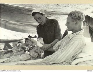 HELDSBACH MISSION, FINSCHHAFEN AREA, NEW GUINEA. 1944-03-13. NFX70245 SISTER N.G. LUKE, OF THE AUSTRALIAN ARMY NURSING SERVICE, ATTENDING VX104799 PRIVATE G.K. ABSON IN A TENT WARD AT THE 2/3RD ..