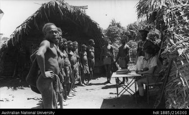 Taken at AUSSIN native village, on the other side of Ramu Post w/ Officer Wright taking a census. Note the luluai near table. 5 Aug 1937  Noon bright