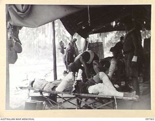 BUIN AREA, BOUGAINVILLE. 1945-09-28. A JAPANESE MEDICAL ORDERLY TREATING PATIENTS AT A REGIMENTAL AID POST ON THE BEACH NEAR KANGU HILL, THE EMBARKATION POINT FOR JAPANESE TROOPS IN THE BUIN AREA. ..