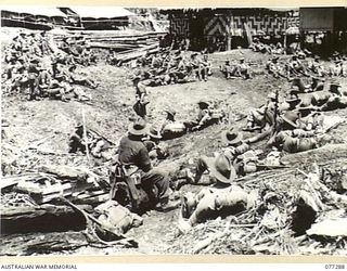 BOUGAINVILLE ISLAND. 1944-11-25. TROOPS OF A COMPANY, 9TH INFANTRY BATTALION RESTING IN A NATIVE LABOUR CAMP AFTER NEGOTIATING A STEEP SECTION OF THE SISIVA TRAIL WHILE ON THEIR WAY TO TAKE OVER ..