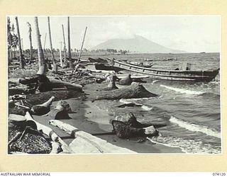 HANSA BAY, NEW GUINEA. 1944-06-17. WRECKED JAPANESE BARGES AMID A SCENE OF DEVASTATION ALONG THE WATERFRONT AFTER THE HEAVY ALLIED BOMBING OF THE AREA