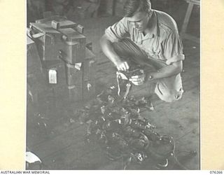 LAE, NEW GUINEA. 1944-09-27. A RADIO MECHANIC CHECKING HEADPHONES IN THE WORKSHOP OF THE 43RD FIELD ORDNANCE DEPOT