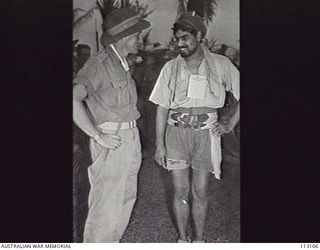 BALIKPAPAN, BORNEO. 1945-08-07. WARRANT OFFICER 2, C.R. HUDSON, 2/2ND CASUALTY CLEARING STATION (1) TALKING TO SIAR GUL (2), A MEMBER OF 2ND BATTALION, 15TH PUNJAB REGIMENT. THIS INDIAN UNIT FOUGHT ..