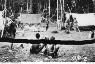 SEPIK RIVER AREA, NEW GUINEA. 1943-08-13. RENDEZVOUS CAMP. STANDING IN FRONT OF THE TENT ARE LEFT TO RIGHT: RAY AH SOONG (WHOSE REAL NAME WAS CHOW CHEN ON), LIEUTENANT HARRY AIKEN, ?, LIEUTENANT ..