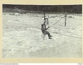 LAE, NEW GUINEA. 1944-08-08. VX117389 SERGEANT C.J. HATTERSLEY, 20TH AUSTRALIAN FIELD COMPANY, ROYAL AUSTRALIAN ENGINEERS TRAVELLING OVER THE SWIFTLY FLOWING BUSU RIVER ON A "FLYING FOX" DURING THE ..