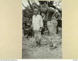 DAGUA, NEW GUINEA. 1945-03-25. VX102 MAJOR J.A.R.K. STRONG, 2/2 FIELD REGIMENT, INTERROGATING AN INDIAN RESCUED FROM THE JAPANESE IN THE WONGINALA MISSION AREA SOUTH OF DAGUA