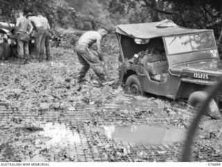 JACQUINOT BAY, NEW BRITAIN. 1944-11-05. TROOPS OF THE 6TH INFANTRY BRIGADE WORKING HARD TO EXTRICATE ONE OF THE UNIT JEEPS WHICH HAD BECOME BOGGED IN THE SAND AT THE UNIT BEACH-HEAD