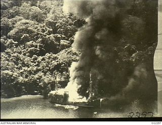 NEW GUINEA. SMOKE BILLOWING UP FROM A CAMOUFLAGED JAPANESE BARGE ON FIRE AFTER BEING SPOTTED AND ATTACKED BY RAAF AIRCRAFT OPERATING IN THE AREA
