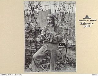 KUNAI RIDGE, NEW GUINEA, 1945-07-11. PTE V.R. CUNNINGHAM, A COMPANY, 2/5 INFANTRY BATTALION, BLACKENS HIS FACE WITH CHARCOAL BEFORE MOVING OUT ON A PATROL WITH NO.9 PLATOON. NO. 8 AND 9 PLATOONS ..