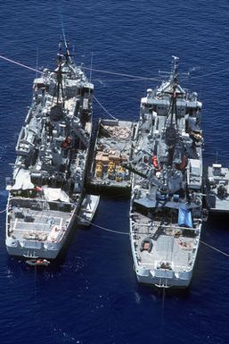 Aerial stern view of the Edenton class salvage and rescue ships USS BRUNSWICK (ATS 3) (left) and USS BEAUFORT (ATS 2) anchored alongside each other with a small service craft between during Pacific Submarine Salvage Exercise 83 (PACSUBSALVEX-83) off the coast of Maui